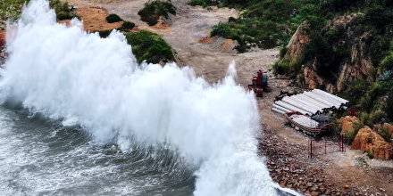 A huge wave crashes onto shore.