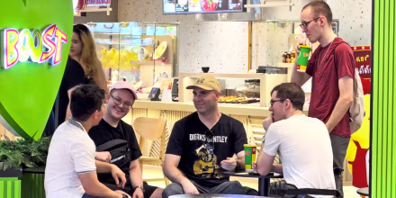Image: A group of men sat at a juice bar table smiling and talking.