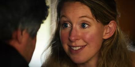 Image: Elizabeth Holmes looking into director Nathan Fielder's eyes.