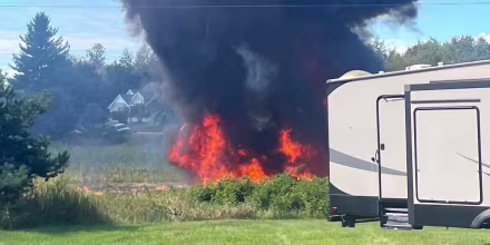 Smoke rises behind a motorhome.