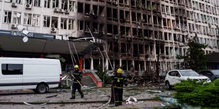 Rescuers gather fire hoses in front of an office building.