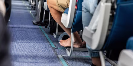 Bare foot airplane passenger with shoes removed during long haul flight for comfort