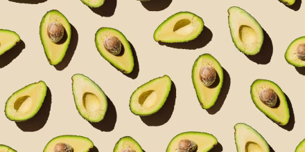 Pattern of fresh ripe green avocado fruit halves on beige background. Healthy food, diet and detox concept. Flat lay, top view