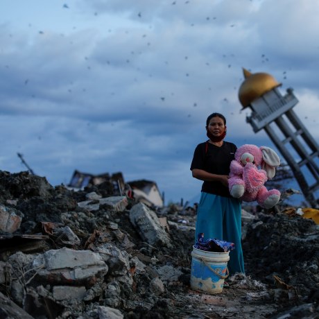 A woman holds a stuffed rabbit toy after it was found at her destroyed home where she said she had lost her three children, in Palu