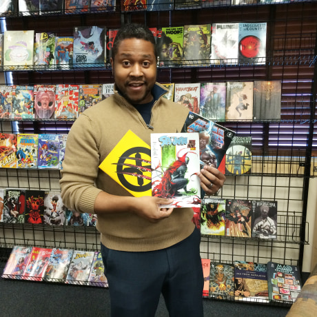 Eric Childs hold comic books inside Mind's Eye Comics store in Burnsville, Minn.