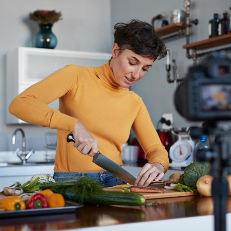Female food vlogger making video while prepping vegetables in kitchen
