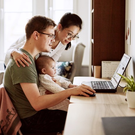 Image: A couple browsing on the computer while sitting with their baby.