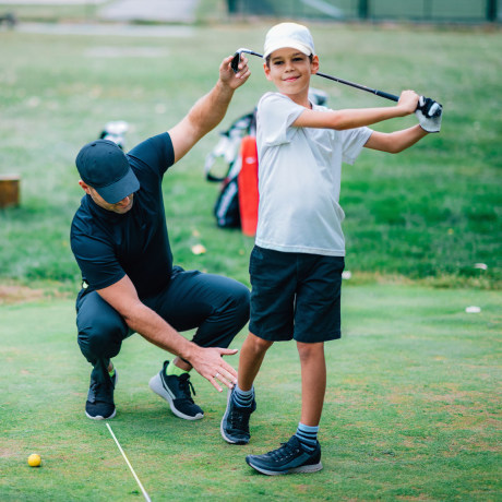 Golf Instructor Teaching Young Boy How to Swing