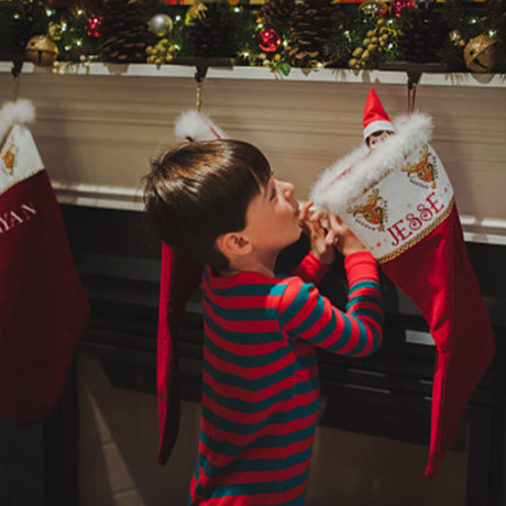 Side view of curious boy looking at toy in sock hanging by fireplace during Christma
