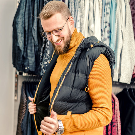 Young man admiring himself looking in a mirror in a menswear shop.