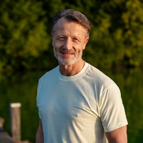 Happy senior man in white t-shirt near lake