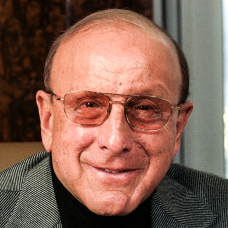 Clive Davis sits at a desk in an office by a window