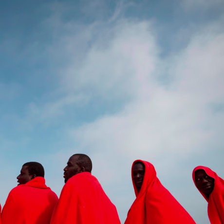Image: A group of migrants warm up with Red Cross blankets