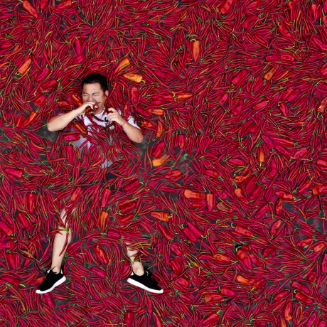 Image: A contestant lays in a pool of red chilies