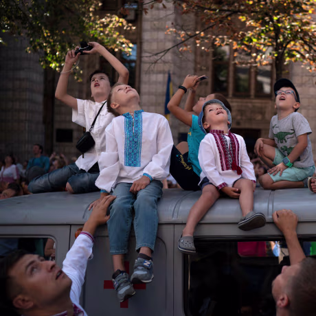 Image: Children look up as aircraft fly above the city center during a military parade to celebrate Independence Day in Kiev