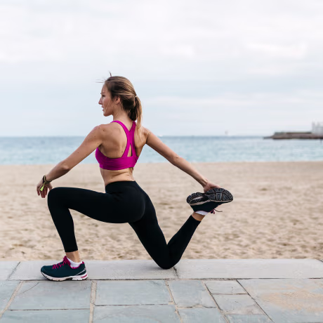 Young woman stretching and warming up for training at the beach