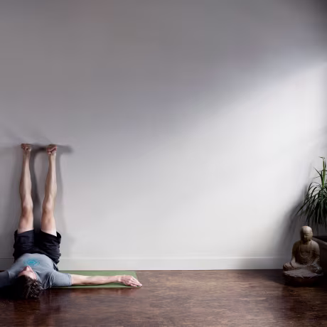 Man lying on floor with his legs stretched out going up wall