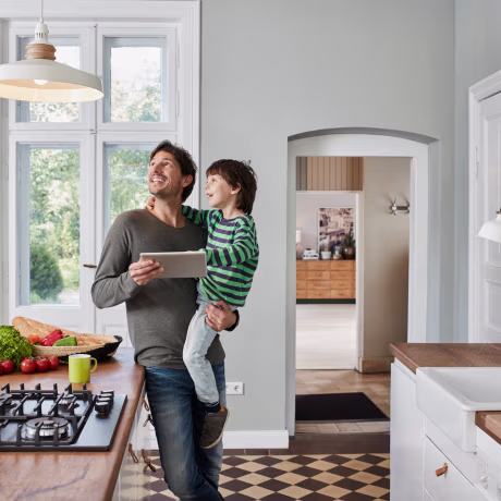 Father and son using tablet in kitchen looking at ceiling lamp