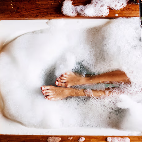 Woman legs in bath foam. Top view. Enjoying and relaxation in spa hotel