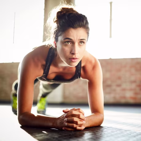 Determined young woman performing plank position in gym