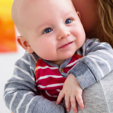 Mother holding baby son over shoulder