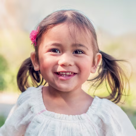 A 2 year old girl smiles as she plays outdoor.