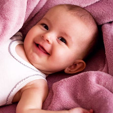Portrait of baby girl smiling wrapped in a soft blanket