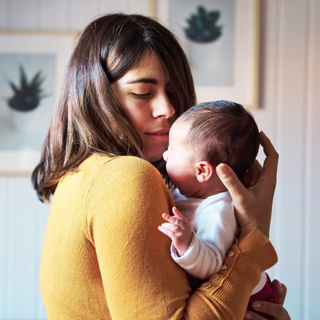 Side view of new mother comforting her newborn while crying.