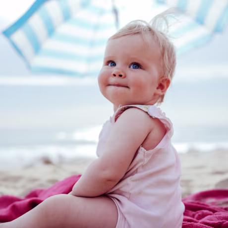Happy little blondhaired toddler girl sitting at the beach.