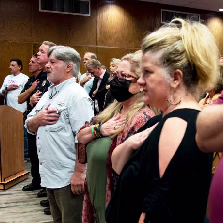 Members of the public hold their hands over their hearts as they say the pledge of allegiance during a Grapevine-Colleyville Independent School District school board meeting at the Grapevine-Colleyville ISD administration building in Grapevine Texas on Monday, Aug. 22, 2022.