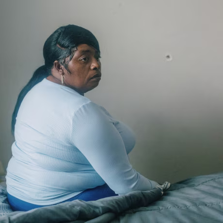 Latasha-Smith on her bed next to the wall with the bullet hole at home in Jackson, Miss.