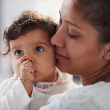 Mother holding baby girl sucking thumb