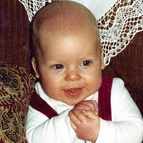 Baby boy back in the eighties sitting on sofa.