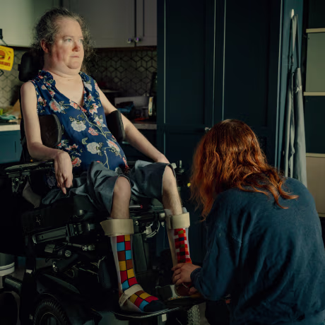 A split composite image of Rebecca Anger having her legs and feet fastened into a wheelchair, and a plant by a windowsill