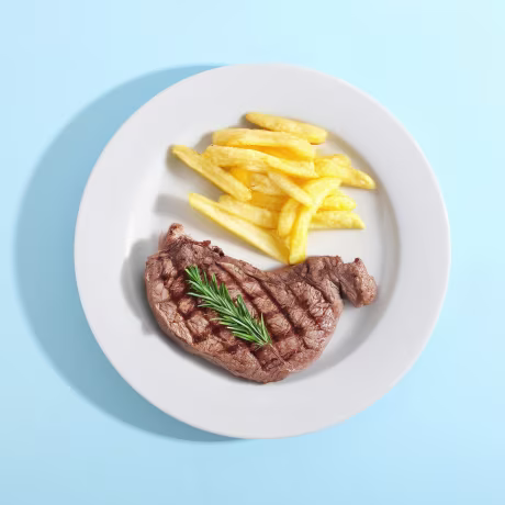 Grilled Steak with French Fries and Rosemary on a White Plate, Top View on Blue Background