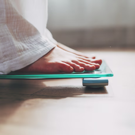 Female feet standing on electronic scales for weight control on wooden background. The concept of slimming and weight loss