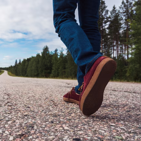 Finland, Lapland, feet of man walking on empty country road
