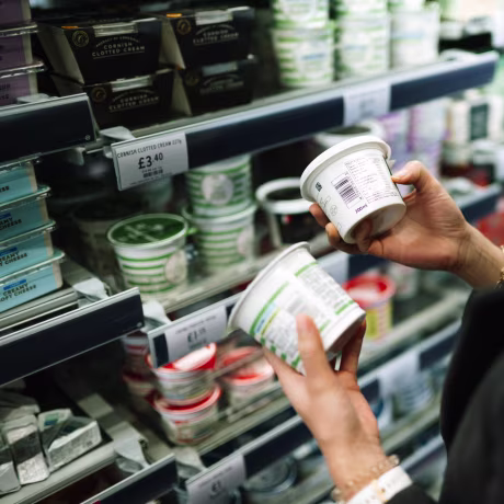 Close-up of shopper comparing nutritional labels on food packaging.