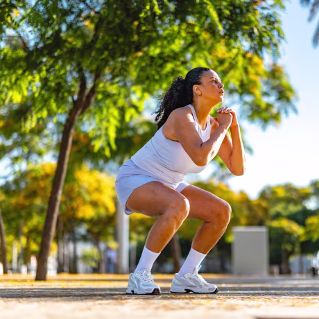 Middle Aged Hispanic Woman Practicing Squats Outdoors In Barcelona Park