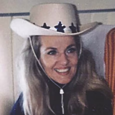 Image: Dee Brock in her younger years, wearing a cowboy hat and smiling.