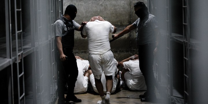 Prisoner led by two security officers inside a cell.