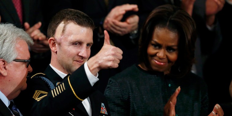 First Lady Michelle Obama (R) applauds U.S. Army Ranger Sgt. First Class Cory Remsburg (C), injured while serving in Afghanistan, during President Barack Obama's State of the Union speech on Capitol Hill in Washington Jan. 28, 2014.