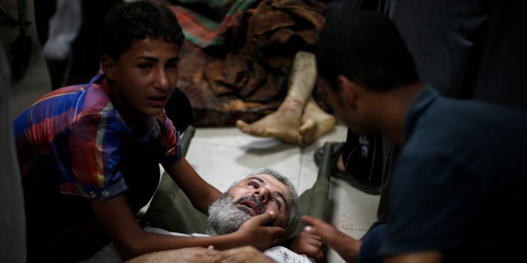 A Palestinian boy comforts his father, whom medics said was wounded by Israeli shelling in Shejaia, at a hospital in Gaza City