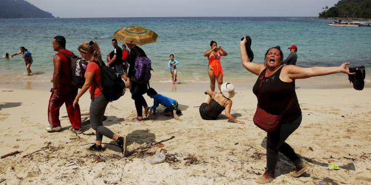 Image: A Cuban migrant shouts \"Cuba\" after arriving to the beach after crossing the border from Colombia through the jungle as tourist stand by in La Miel, in the province of Guna Yala, Panama