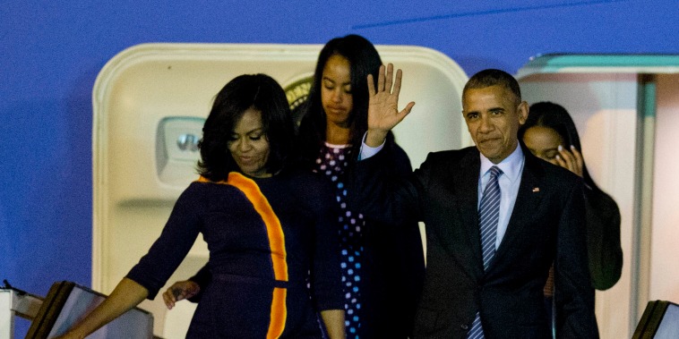 President Barack Obama waves from Air Force One as he arrives accompanied by first lady Michelle and daughters Sasha, behind right, and Malia at the international Buenos Aires airport, Argentina, early Wednesday, March 23, 2016.