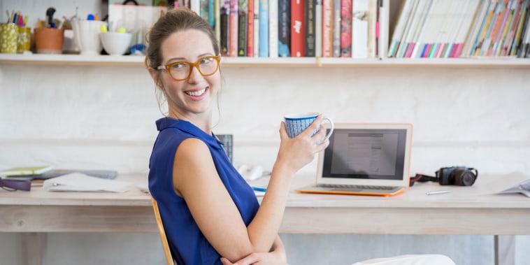 Image: Young woman sits with mug in home office