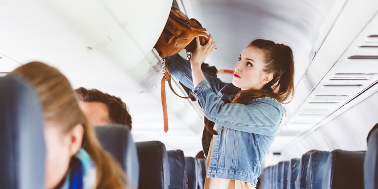 Female airplane passenger storing handbag in locker