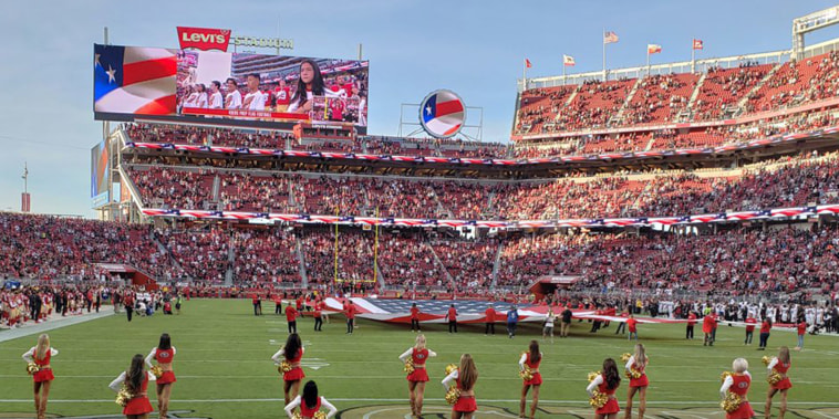 Image: A San Francisco 49ers cheerleader kneels during the national anthem