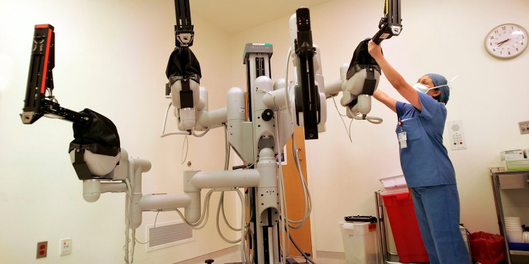 Image: A registered nurse adjusts the robotic arms before an automated calibration of the Da Vinci robot that will be used in surgery at the Helford Clinical Research Hospital in Duarte