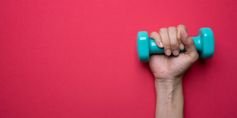 A woman holds a dumbbell